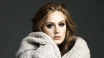 HD desktop wallpaper of English singer Adele wrapped in a cozy knitted garment against a dark background.