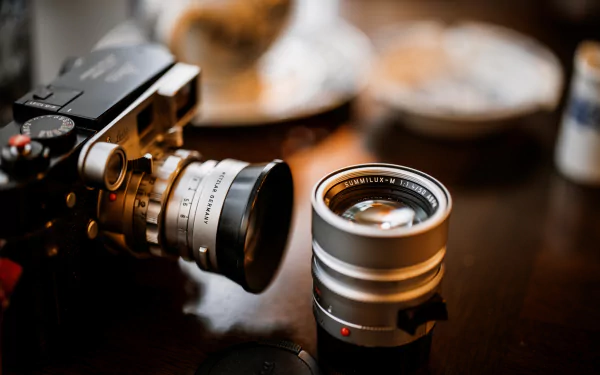 Close-up of a vintage camera and an additional lens on a wooden surface with a blurred background, captured in HD for a man-made, lens-focused desktop wallpaper.