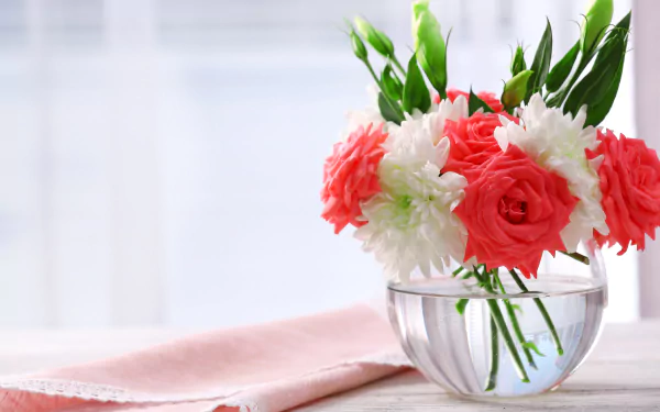 A 4K Ultra HD still life photograph of red roses, white eustoma flowers, and green leaves arranged in a clear vase beside a folded handkerchief on a bright surface.