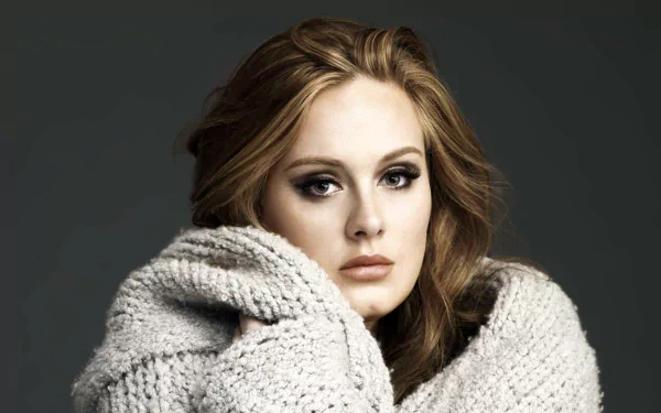 HD desktop wallpaper of English singer Adele wrapped in a cozy knitted garment against a dark background.