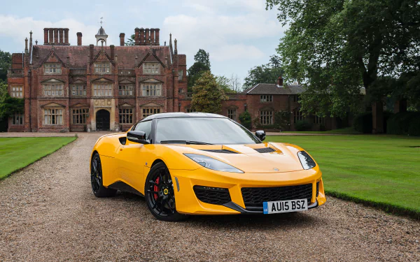 Yellow Lotus Evora sports car parked on a gravel driveway in front of a large historic mansion with green lawns, captured in 4K Ultra HD quality.