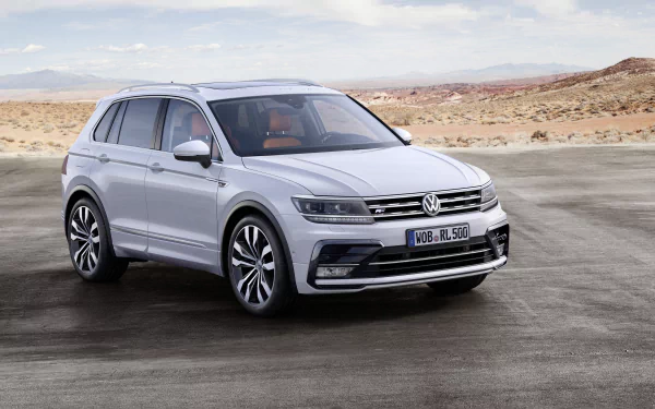 White Volkswagen Tiguan SUV parked on an open road with a desert landscape in the background, captured in sharp 4K Ultra HD quality.