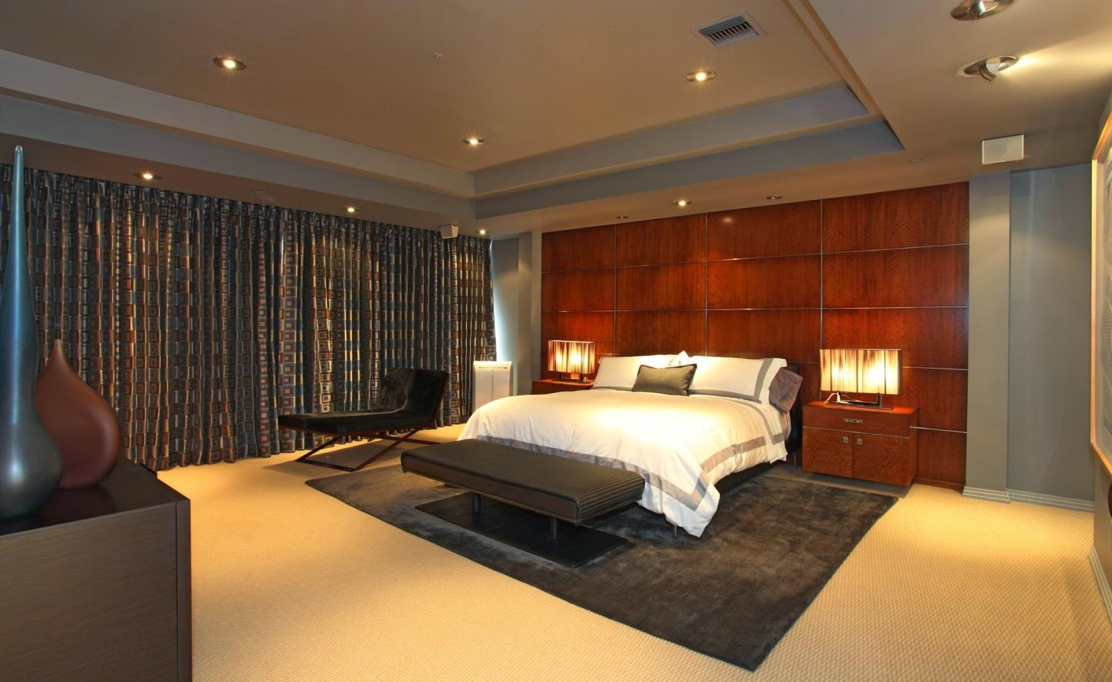 HD PC desktop wallpaper of a modern man-made bedroom: a bed with pillows, bedside lamps, dark rug, wooden paneled wall and curtains.