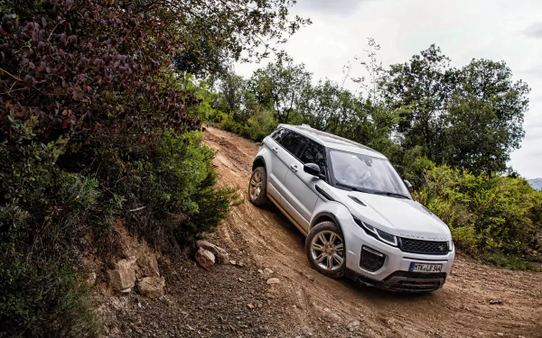 A white Land Rover Range Rover Evoque navigates a rugged terrain, surrounded by greenery, captured in stunning 4K Ultra HD quality for a dynamic desktop wallpaper.