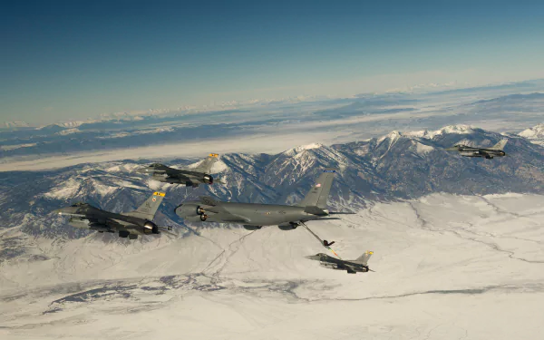 A formation of military aircraft including a Boeing KC-135 Stratotanker refueling General Dynamics F-16 Fighting Falcon jet fighters over snowy mountain terrain.