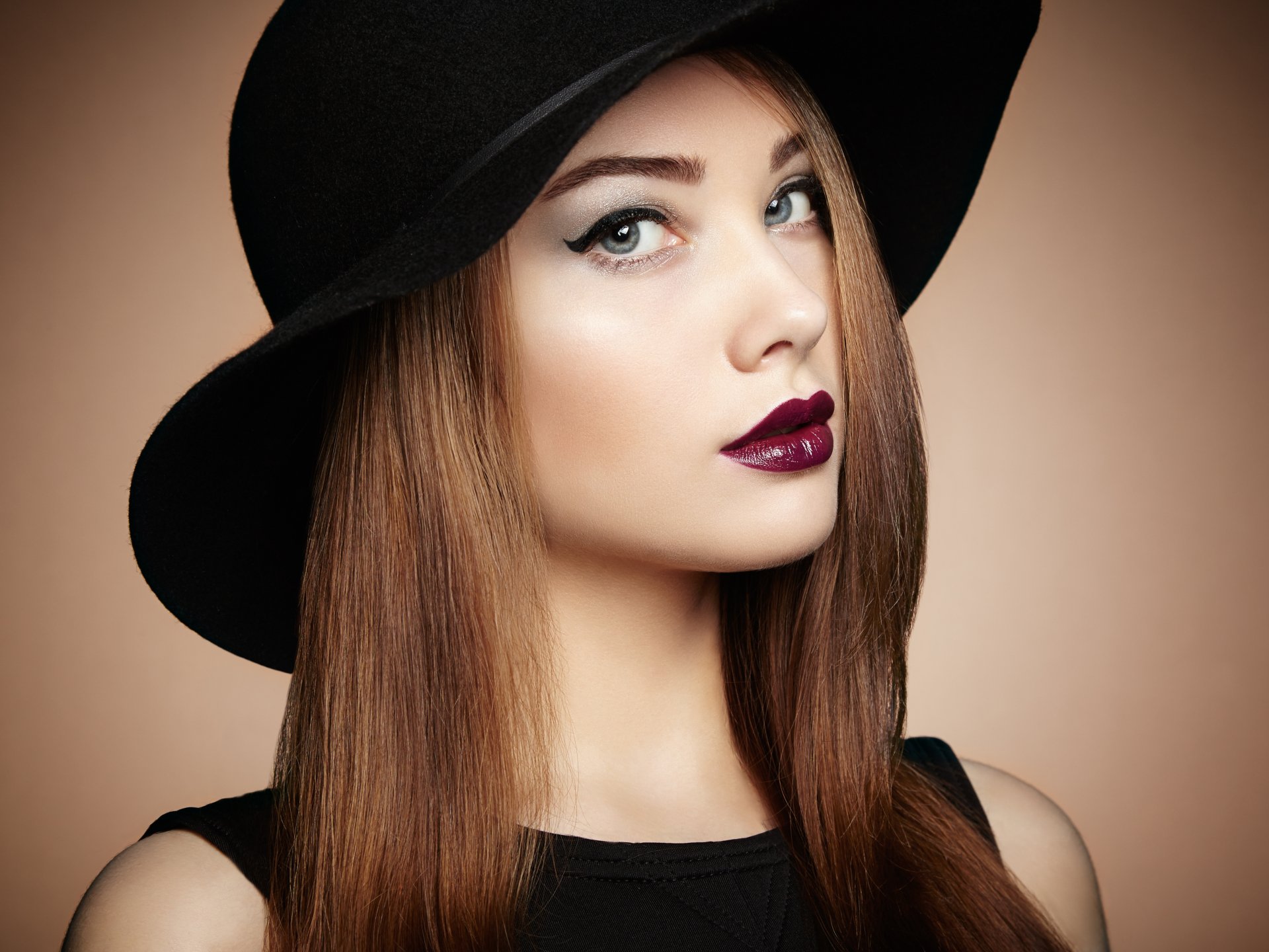 Close-up portrait of a brunette woman with blue eyes and dark lipstick, wearing a black hat, captured in stunning 8K Ultra HD quality for PC desktop wallpaper.