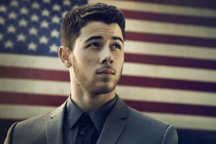 HD desktop wallpaper of Nick Jonas in a suit, with the American flag in the background.