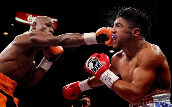 Floyd Mayweather delivers a powerful punch to his opponent in this dynamic boxing scene, capturing the intensity of sports in a striking HD desktop wallpaper.