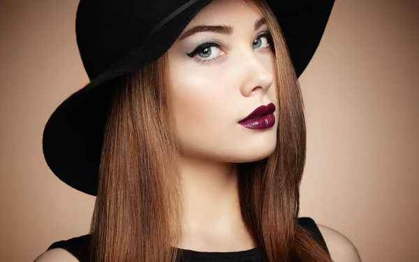 Close-up portrait of a brunette woman with blue eyes and dark lipstick, wearing a black hat, captured in stunning 8K Ultra HD quality for PC desktop wallpaper.