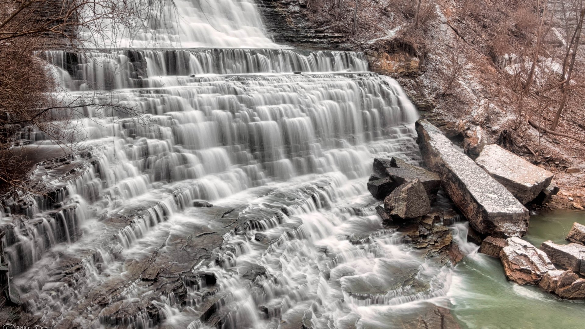 Albion Falls in Canada cascades over rugged rocks, surrounded by natural woodland, captured in a high-definition desktop wallpaper showcasing the beauty of this scenic waterfall.