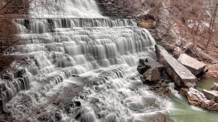 Albion Falls in Canada cascades over rugged rocks, surrounded by natural woodland, captured in a high-definition desktop wallpaper showcasing the beauty of this scenic waterfall.