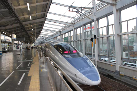 4K Ultra HD image of a sleek bullet train at a modern train station in Japan, showcasing advanced vehicle design and urban transit infrastructure.