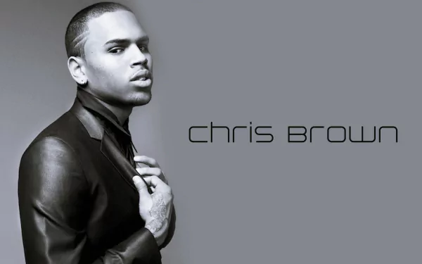 HD PC desktop wallpaper featuring Chris Brown in a leather jacket against a gray background with his name in modern black text, emphasizing music and style.