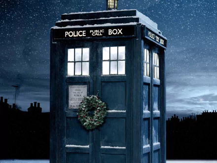 HD desktop wallpaper featuring the TARDIS from Doctor Who (2005) decorated with a Christmas wreath, set against a starry night sky.
