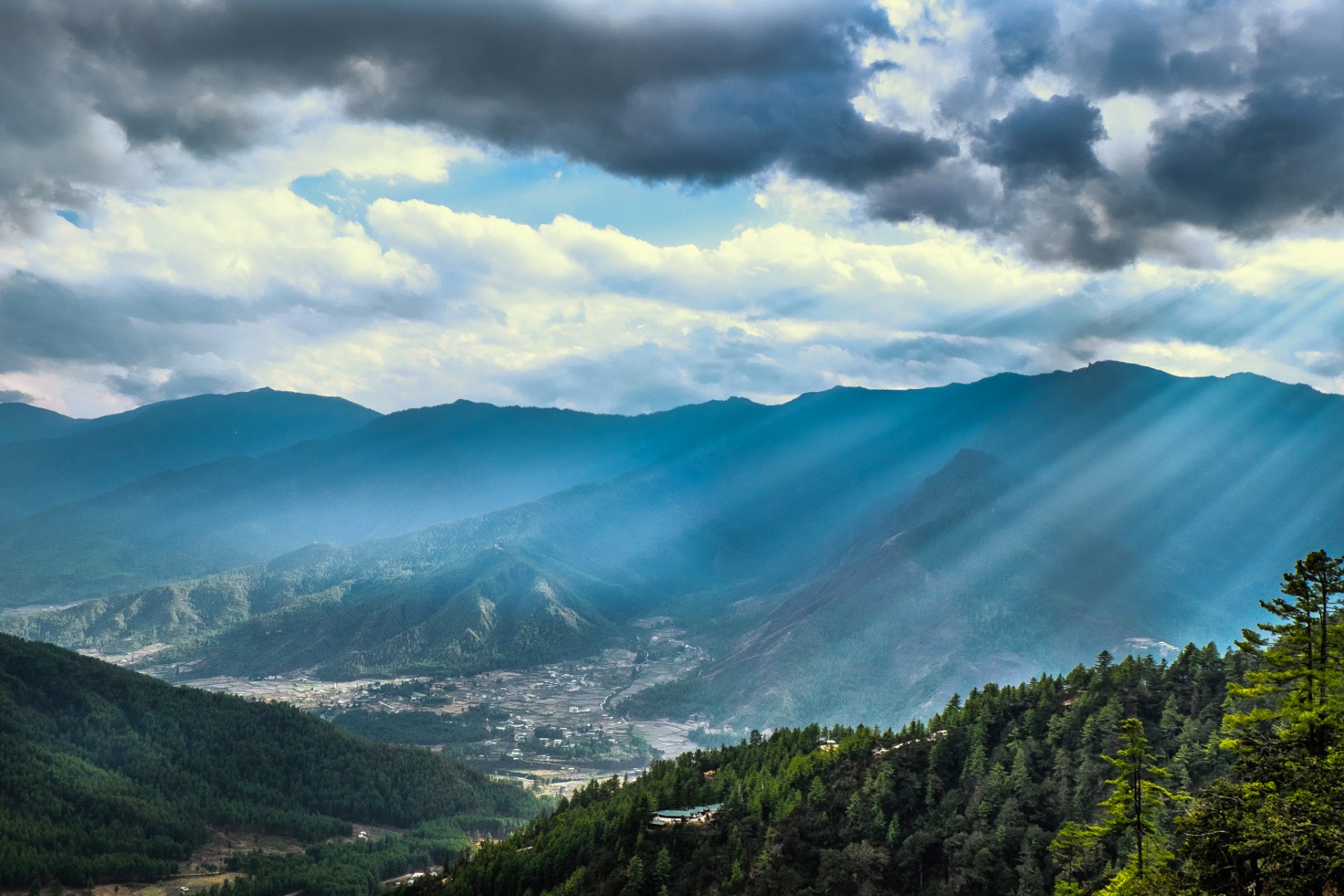 HD PC desktop wallpaper and background: landscape photography of sunbeams breaking through clouds over a forested mountain valley.