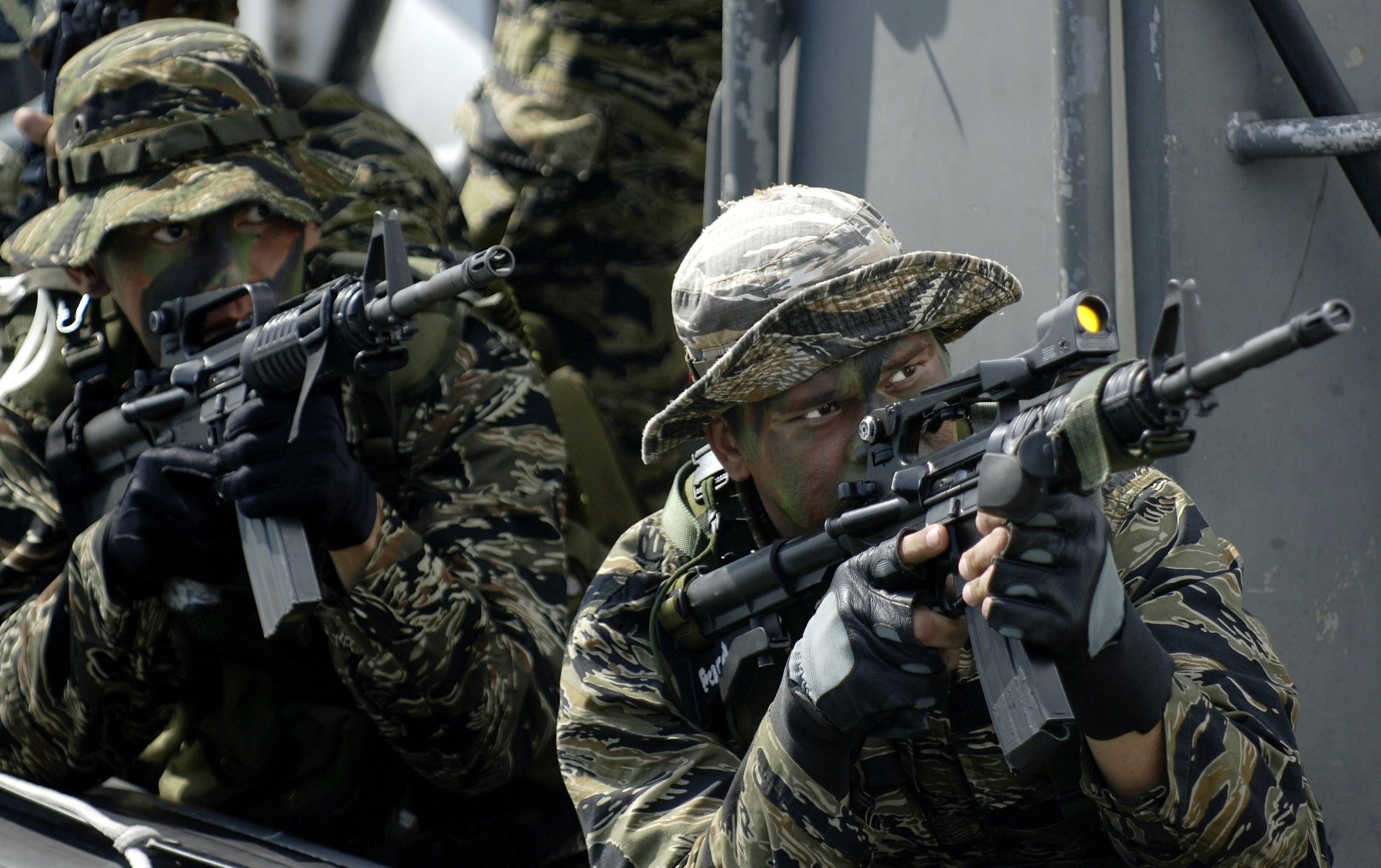 Navy SEAL soldiers in camouflage gear aiming rifles aboard a military vessel, captured in a high-definition image suitable as a PC desktop wallpaper.