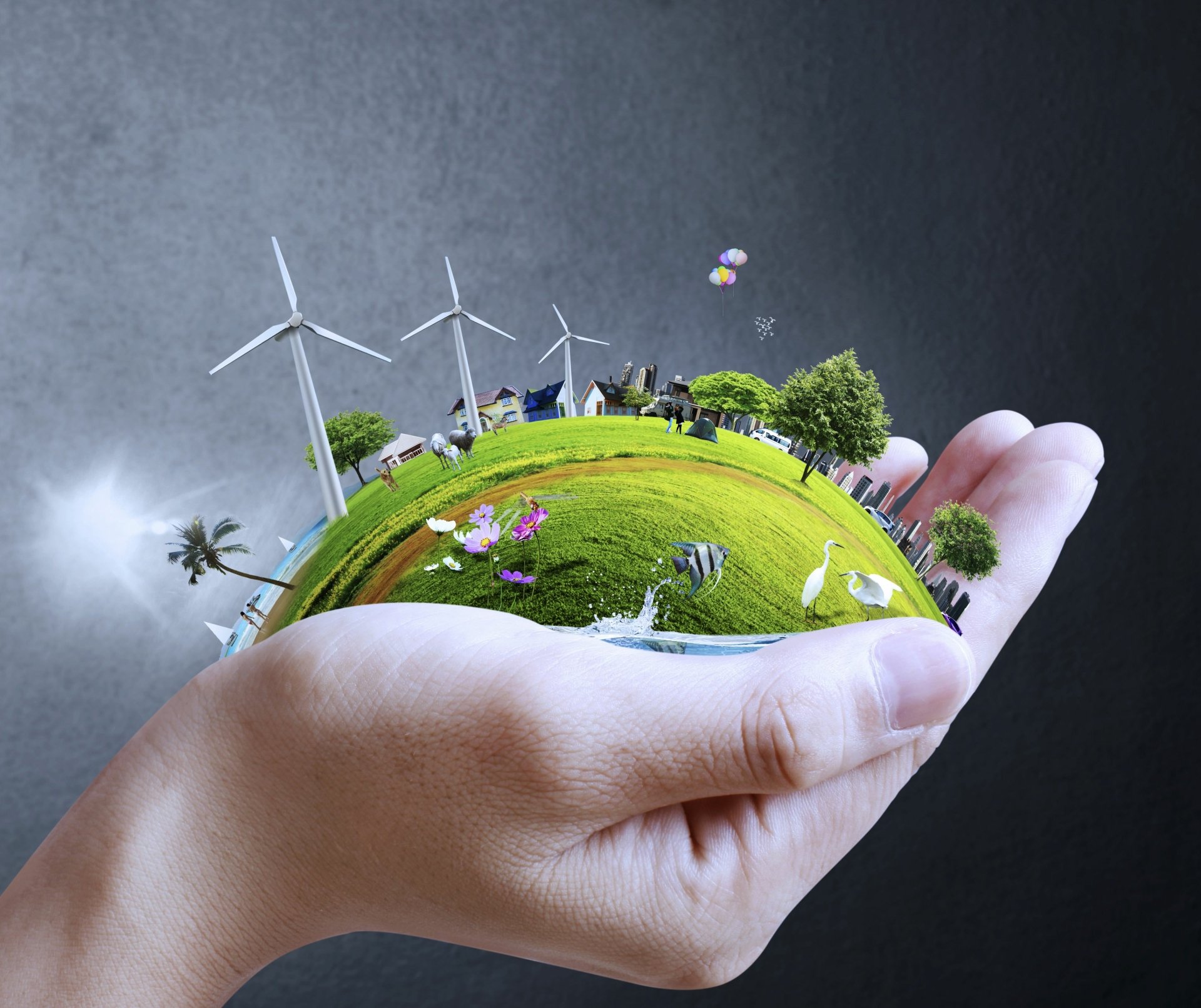 Holiday Earth Day 2K Quad HD PC desktop wallpaper and background: hands cradle a miniature green planet with wind turbines, trees, houses, birds and butterflies.