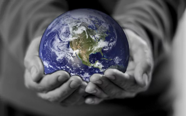 Earth Day holiday 2K Quad HD PC desktop wallpaper and background: vibrant Earth cradled in grayscale hands against a blurred monochrome backdrop.