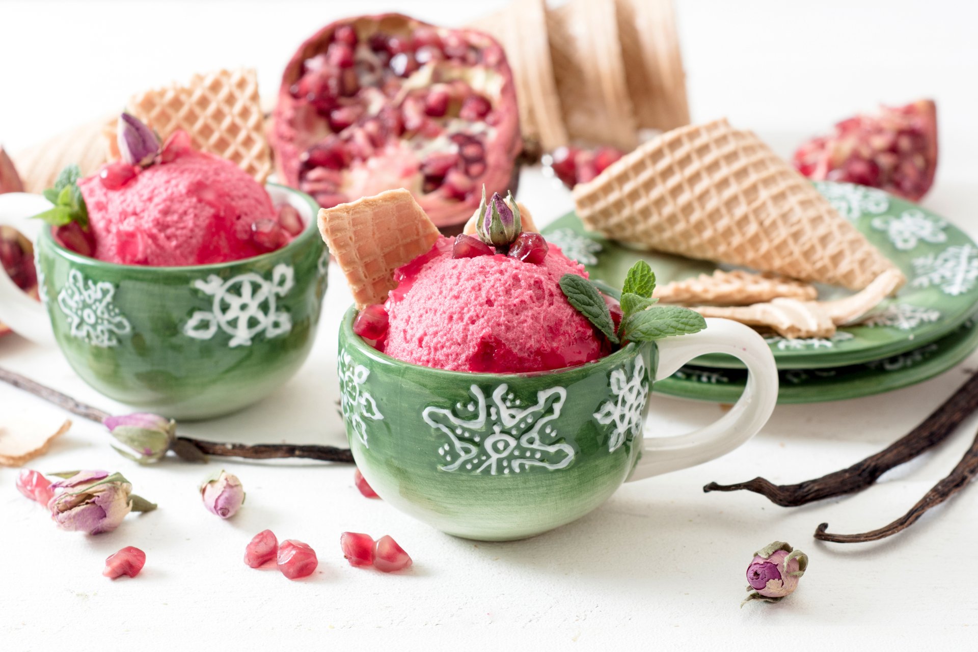 A vibrant summer dessert of pink ice cream served in green cups with waffle cones, garnished with mint and pomegranate seeds, captured in 4K Ultra HD quality.