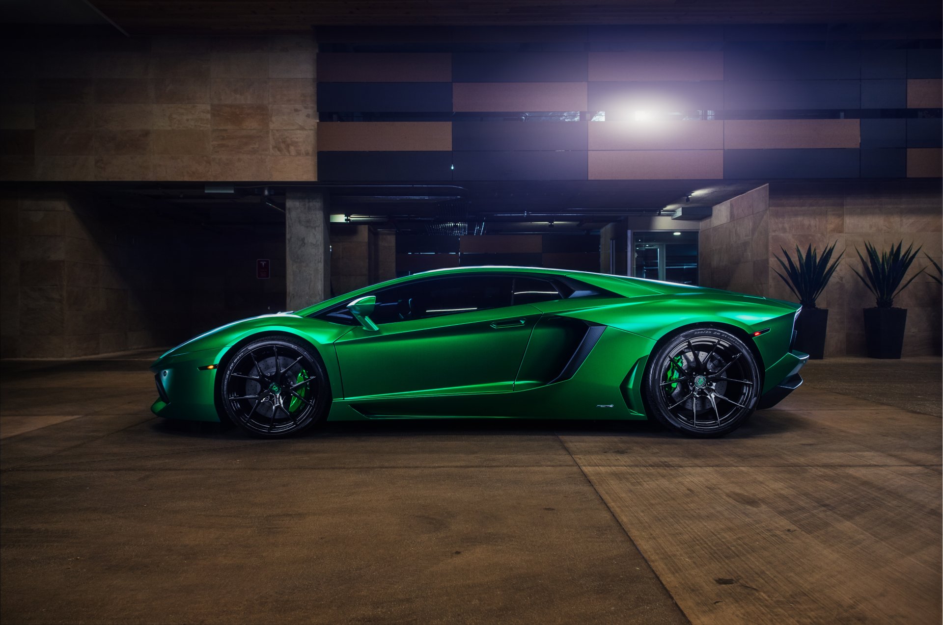 A vibrant green Lamborghini Aventador supercar showcased in a dimly lit, modern parking area, captured in 4K Ultra HD for a striking PC desktop wallpaper background.