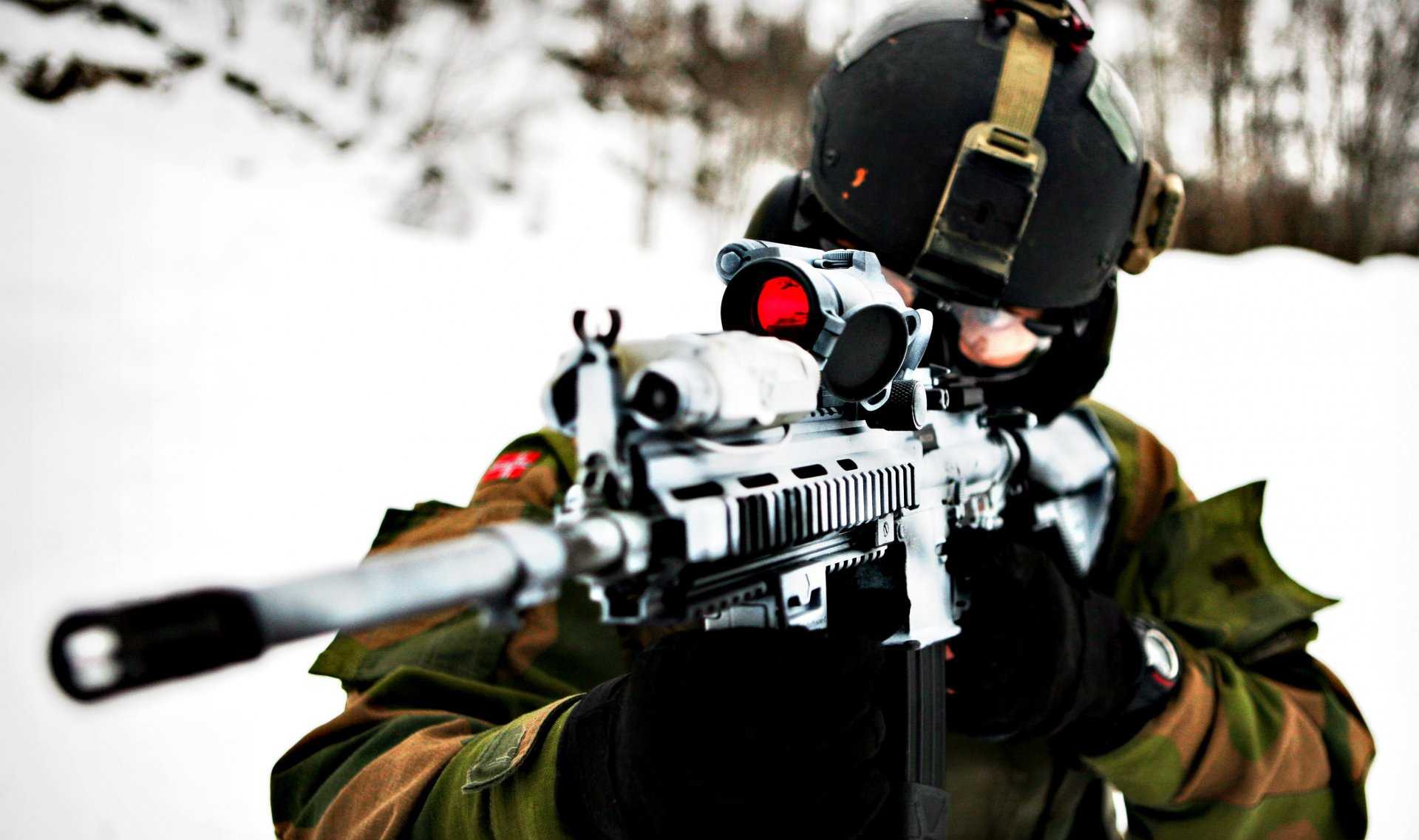 A high-definition desktop wallpaper and background image featuring a military sniper aiming through the scope of a rifle in a snowy outdoor setting.