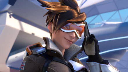 HD desktop wallpaper featuring Tracer from the video game Overwatch. Tracer is depicted with her signature goggles and confident smile, set against a futuristic background.
