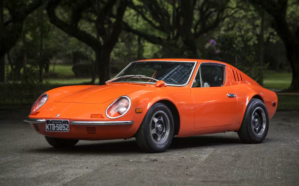 Orange Puma GT supercar parked on a tree-lined road, presented as a 4K Ultra HD PC desktop wallpaper background.