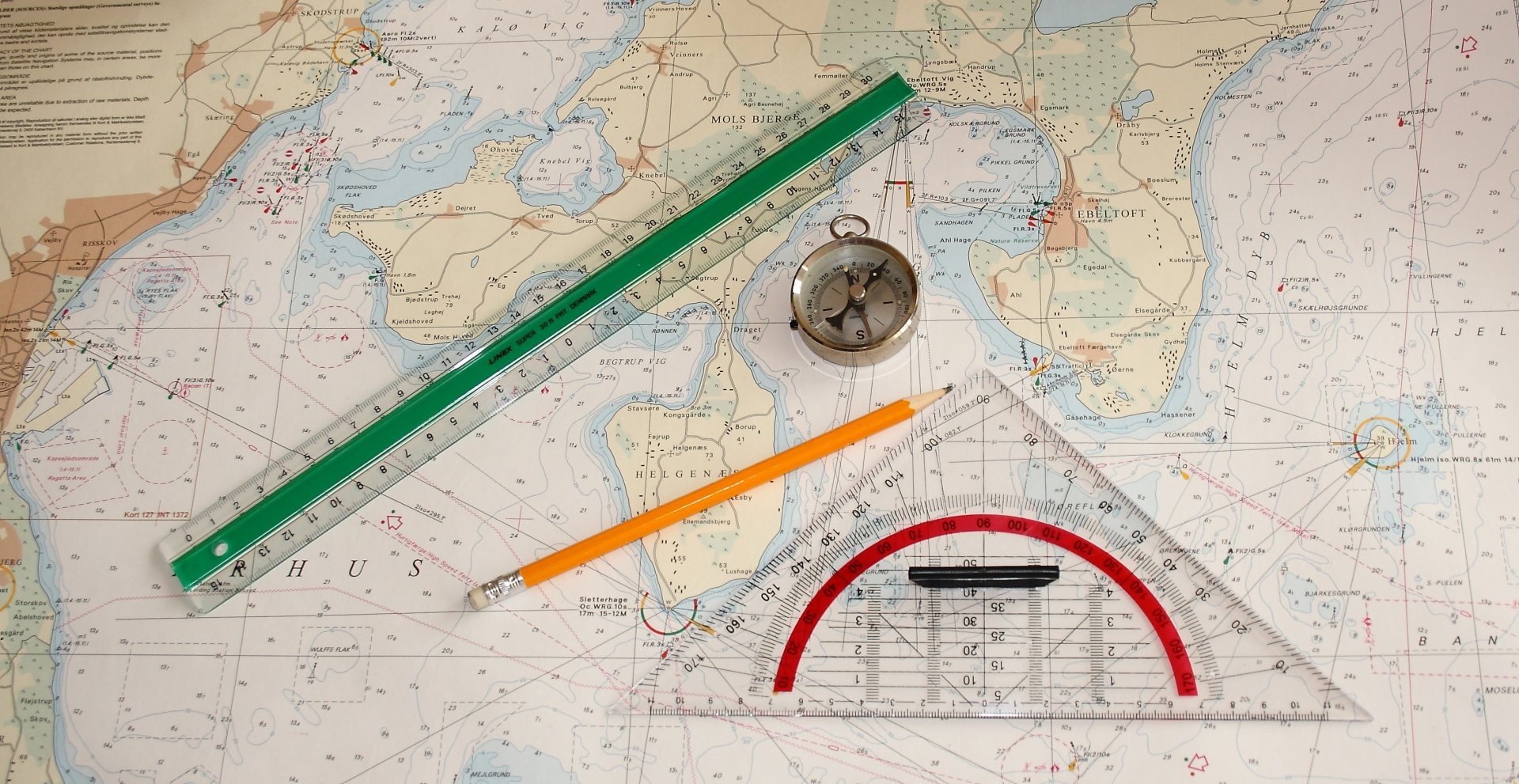 Still life of navigation tools including a compass, pencil, ruler, and protractor arranged on a maritime chart, designed as an HD PC desktop wallpaper background.