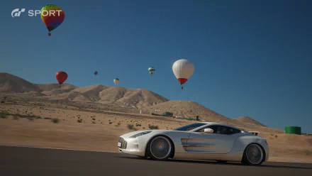HD PC desktop wallpaper featuring a sleek white sports car racing on a desert road with colorful hot air balloons drifting in the sky, inspired by Gran Turismo Sport.