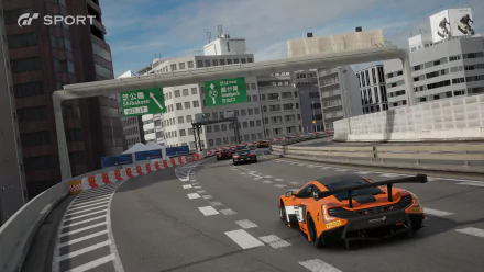 Gran Turismo Sport video game HD PC desktop wallpaper/background: orange GT race car rounds a curved elevated city highway with rivals ahead, city buildings and green overhead signs.