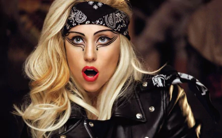Close-up of an American singer with hazel eyes, blonde hair, bold makeup, red lipstick, wearing a black bandana and leather jacket, captured in an HD desktop wallpaper.