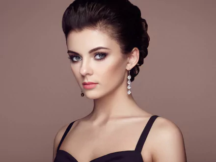 HD desktop wallpaper featuring a brunette woman model wearing elegant dangling earrings against a soft brown background.
