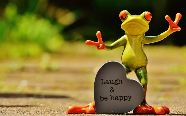 A vibrant frog figurine stands beside a heart-shaped stone that reads Laugh & be happy, set against a lush background in this motivational 4K Ultra HD wallpaper.