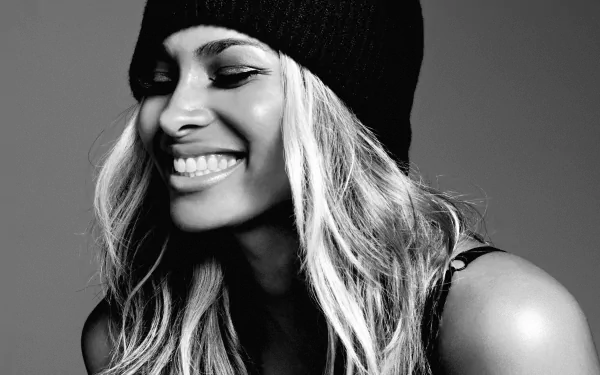 Black-and-white HD desktop wallpaper: smiling woman in a knit beanie with long hair, radiating a musical, stylish energy.