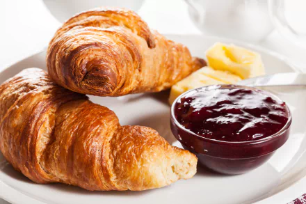 A delicious breakfast scene featuring buttery croissants served with jam and a side of butter, all set against a bright, inviting background in 4K Ultra HD.