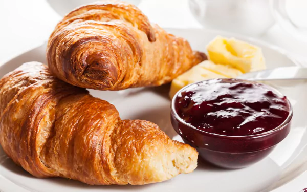 A delicious breakfast scene featuring buttery croissants served with jam and a side of butter, all set against a bright, inviting background in 4K Ultra HD.
