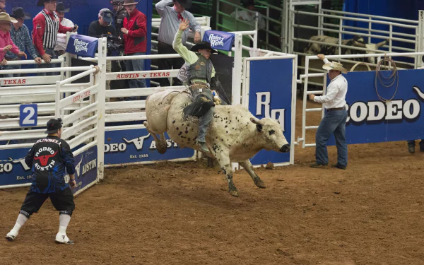 HD desktop wallpaper capturing a dynamic rodeo moment with a cowboy riding a bull in a packed arena, showcasing intense rodeo sports action.