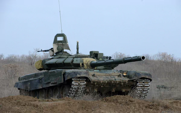 A T-72 military tank stands prominently on rugged terrain, showcasing its detailed design and powerful stance, set against a clear sky, suitable for a high-definition desktop wallpaper.