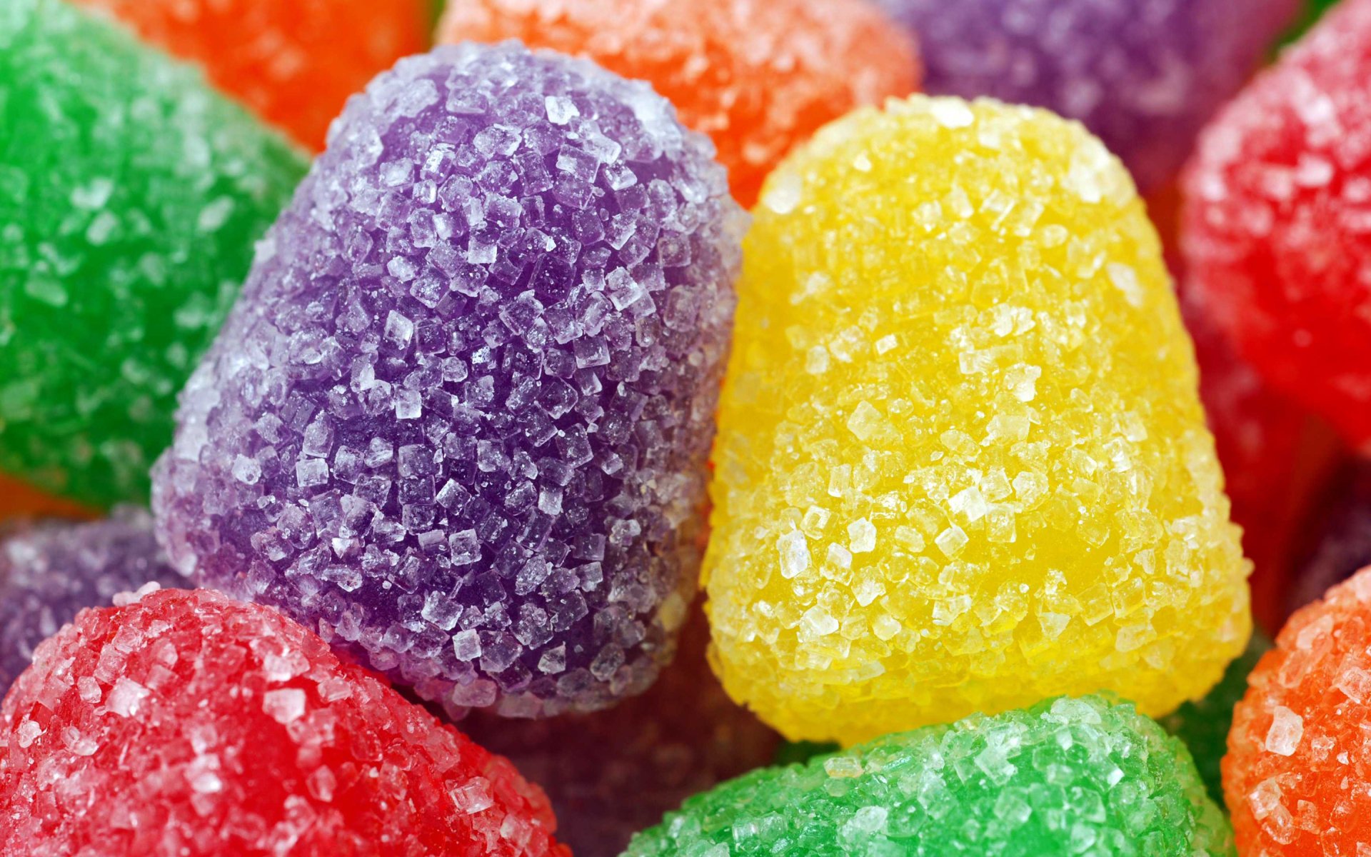 Close-up HD desktop wallpaper of colorful sugary gumdrops, featuring vibrant reds, greens, yellows, oranges, and purples, highlighting the texture of these sweet candies.