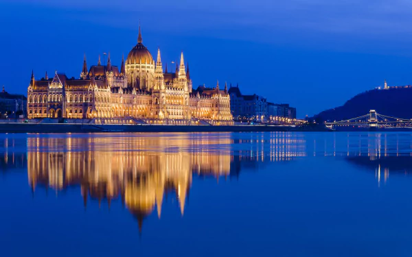 Night view of the illuminated Hungarian Parliament Building in Budapest, Hungary — a man-made architectural monument reflected on the Danube River.