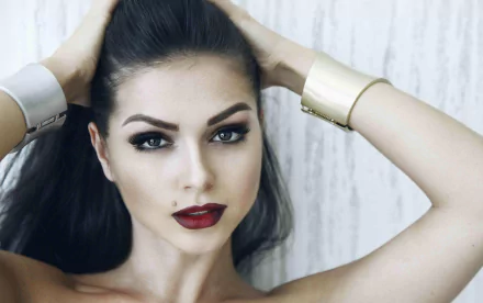 HD desktop wallpaper: close-up portrait of a brunette singer with brown eyes and bold lipstick, hands in her hair and a confident, music-artist expression.