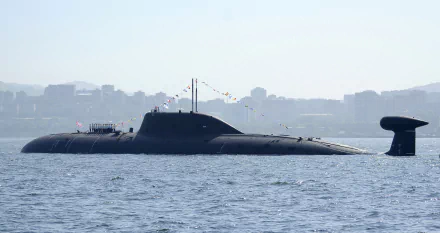 A sleek military submarine adorned with colorful flags surfaces in calm waters, with a city skyline visible in the background, making for a striking HD desktop wallpaper.