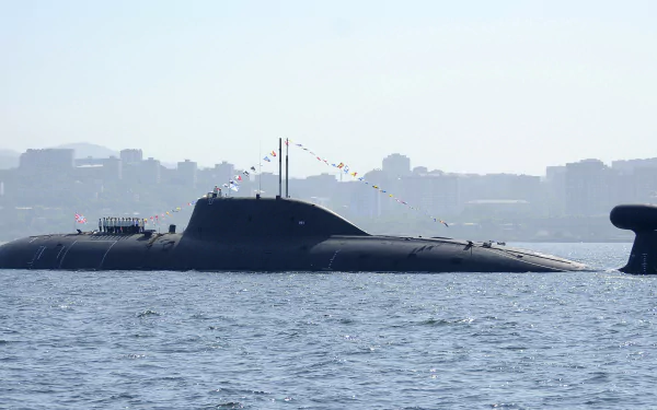 A sleek military submarine adorned with colorful flags surfaces in calm waters, with a city skyline visible in the background, making for a striking HD desktop wallpaper.