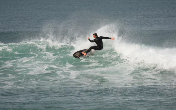 Surfer carving a wave on the ocean, dynamic surfing action amid crashing ocean waves — 2K Quad HD PC Desktop Wallpaper and Background.