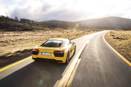 Yellow Audi R8 V10 supercar driving on a winding road in a scenic, arid landscape, captured in stunning 4K Ultra HD for a PC desktop wallpaper background.