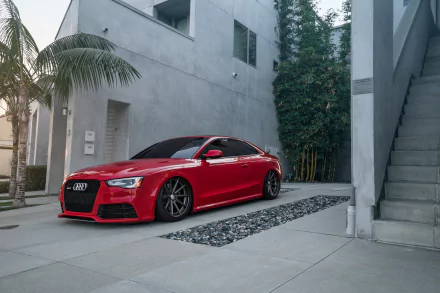 HD desktop wallpaper featuring a sleek red Audi A5 parked in a modern, minimalist courtyard with concrete and greenery.