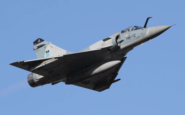 A Dassault Mirage 2000 military jet fighter soars through a clear blue sky, showcasing its aerodynamic design in this high-definition desktop wallpaper.