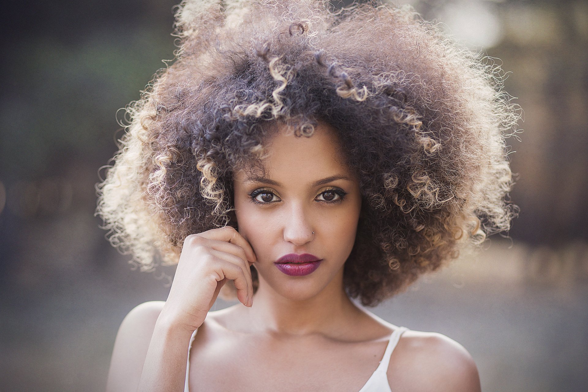HD PC desktop wallpaper of a brunette model with voluminous curly hair, brown eyes and bold lipstick, posing with a confident, direct gaze.