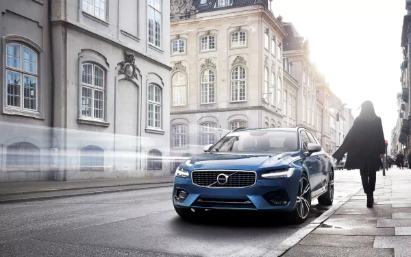 4K Ultra HD desktop wallpaper featuring a blue Volvo S90 parked on a city street beside historic buildings, capturing the sleek design of the Volvo vehicle in natural light.