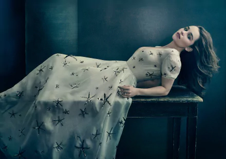 HD PC desktop wallpaper of celebrity Emilia Clarke reclining on a bench, wearing an elegant dress with a dark, moody background.